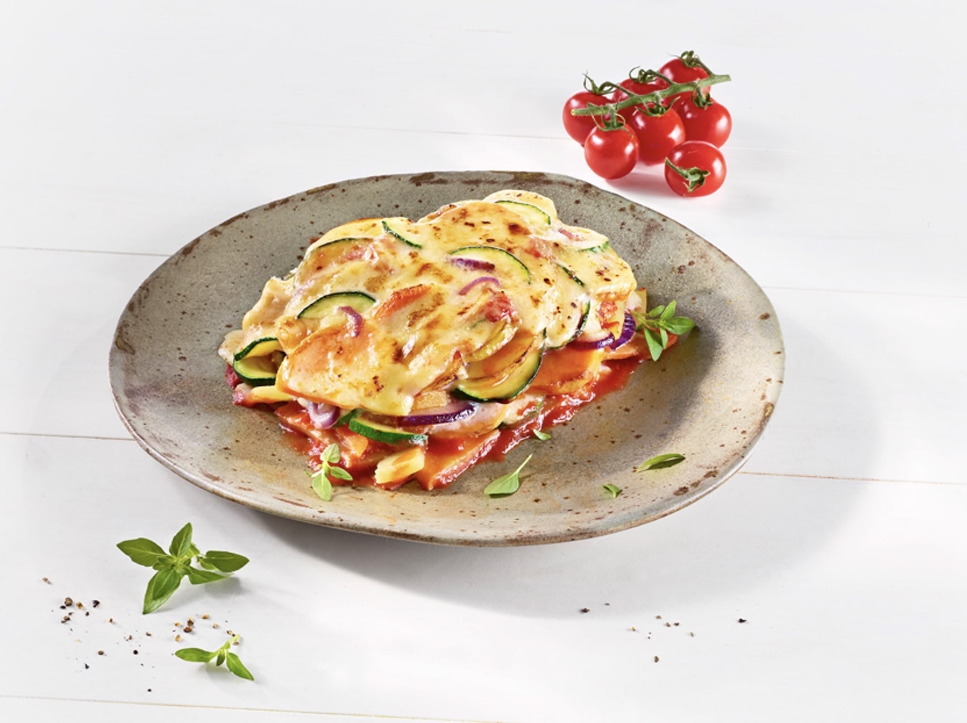 Tellergericht mit einer Portion Gemüseauflauf und mit MILRAM Gouda-Alternative überbacken Tellergericht mit einer Portion Gemüseauflauf und mit MILRAM Gouda-Alternative überbacken