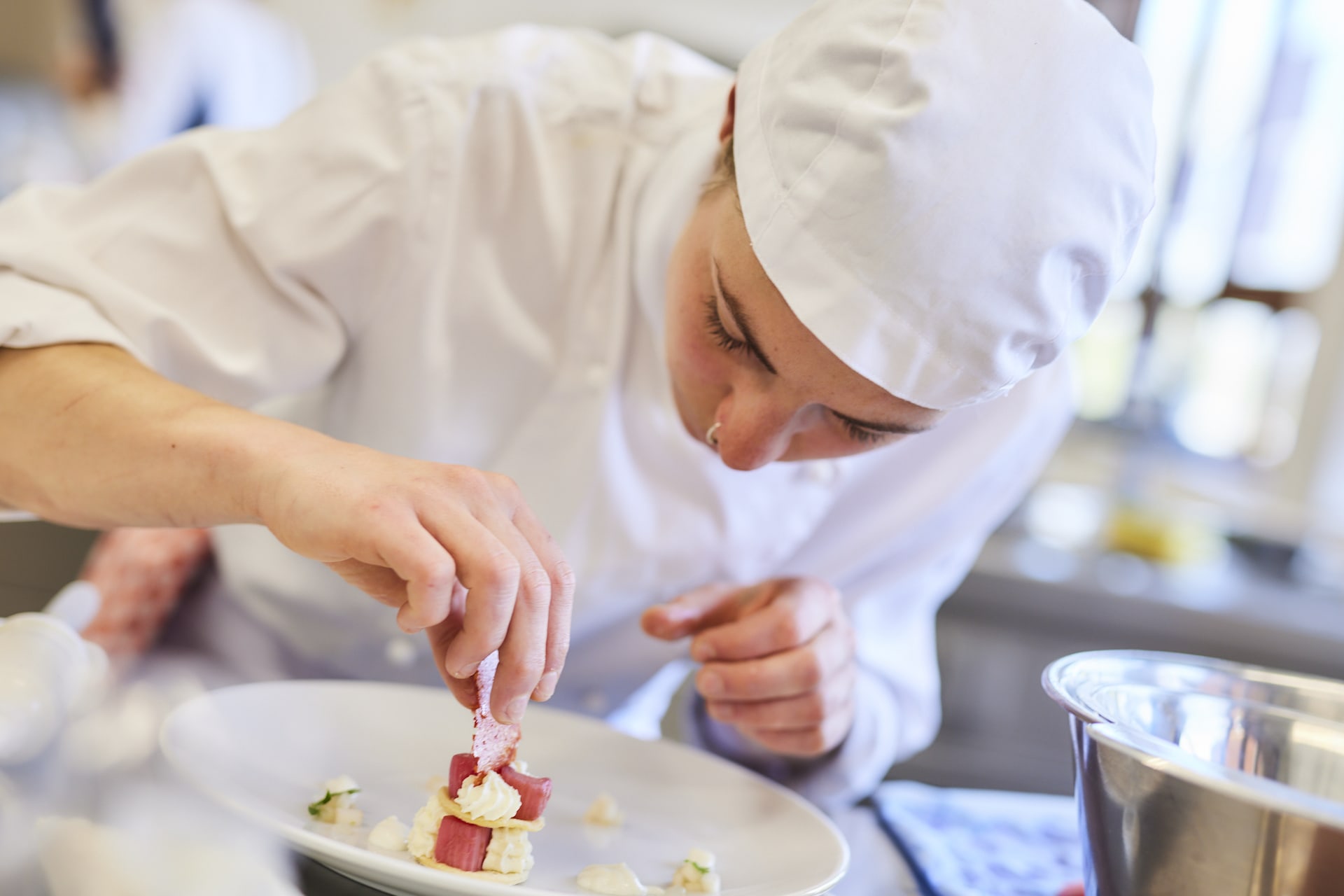Junge Köchin arrangiert einen Dessertteller Junge Köchin arrangiert einen Dessertteller