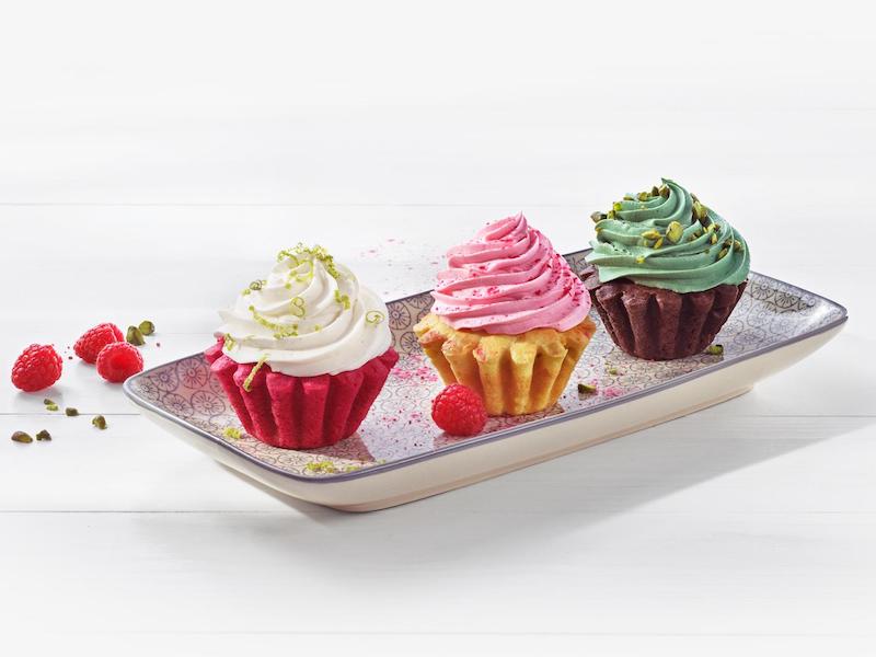 Drei bunt gefärbte Cupcakes auf einem Teller
