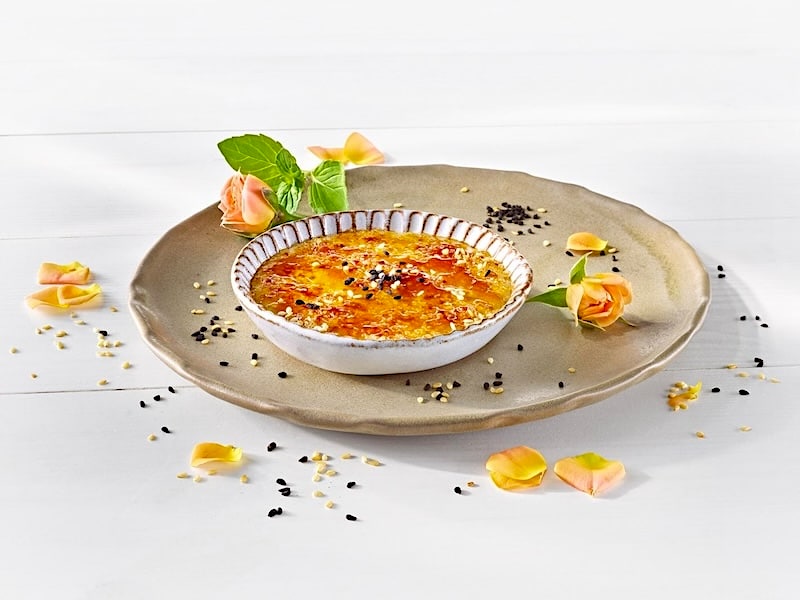 MILRAM Créme Brûlée serviert als Tartelette; daneben ein Ananas-Salat garniert mit Ananas-Esspapier