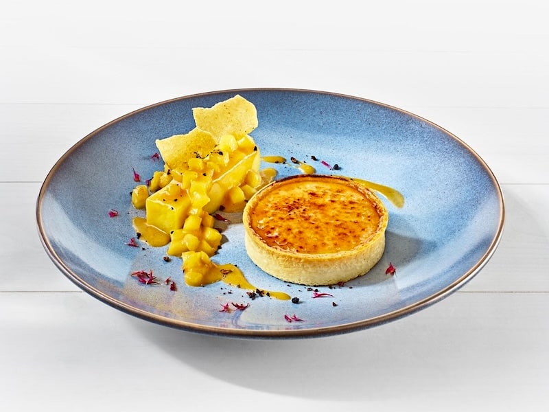 MILRAM Créme Brûlée serviert als Tartelette; daneben ein Ananas-Salat garniert mit Ananas-Esspapier