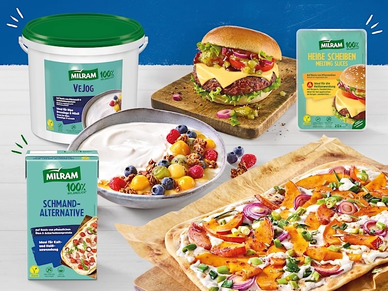Käseburger auf einem Holzbrett, Joghurt mit Früchten in einer Schale und ein Kürbis-Flammkuchen; daneben die Packshots von MILRAM Heiße Scheiben, MILRAM Schmand-Alternative und MILRAM VeJog Joghurt-Alternative