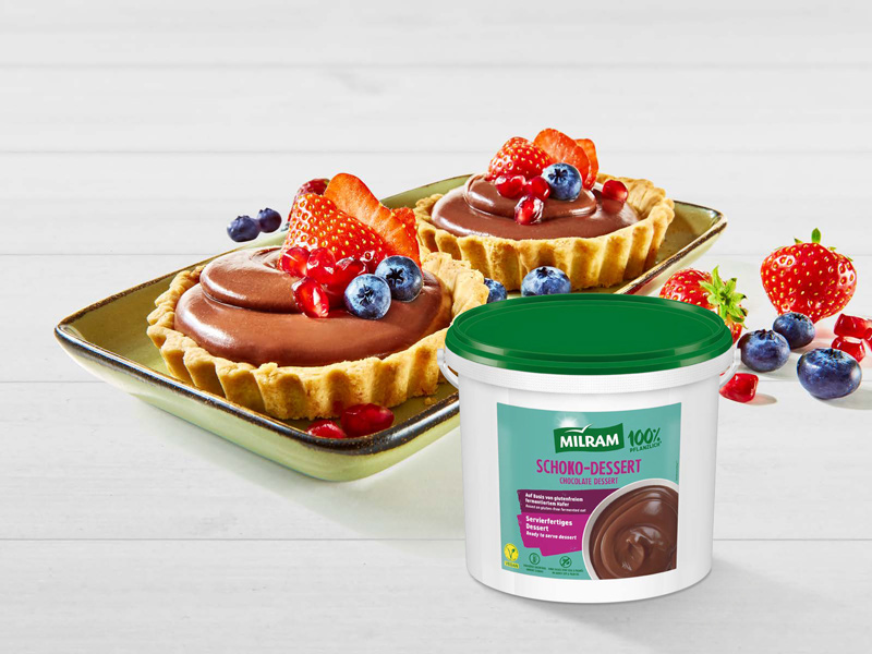 Zwei Tartelettes gefüllt mit MILRAM Schoko-Dessert und einem Topping aus frischen Erdbeeren, Heidelbeeren und Cranberrys