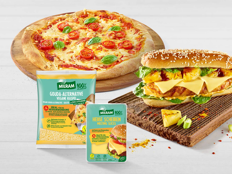Pizza Margaritha auf einem runden Holzbrett belegt mit MILRAM Gouda-Alternative Vegane Raspel