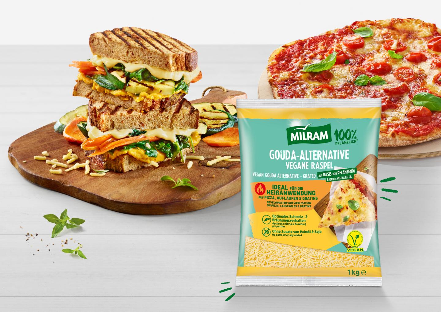 Im Hintergrund links Sandwiches mit Käse und Gemüse, rechts daneben Holzbrett mit Pizza, davor MILRAM Gouda-Alternative als Raspel im 1-kg-Beutel und als 1,5-kg-Block
