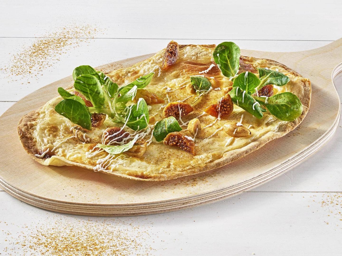 Flammkuchen mit Käse, Feigen und Feldsalat auf Holzbrett Flammkuchen mit Käse, Feigen und Feldsalat auf Holzbrett