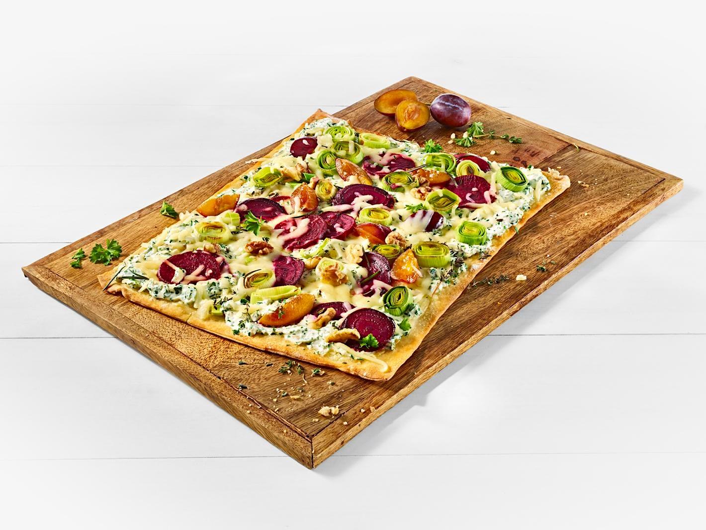 Rechteckiger Flammkuchen auf einem Holzbrett, mit MILRAM Schmand, Rote Bete, Pflaumen, Lauch und MILRAM Mozzarella